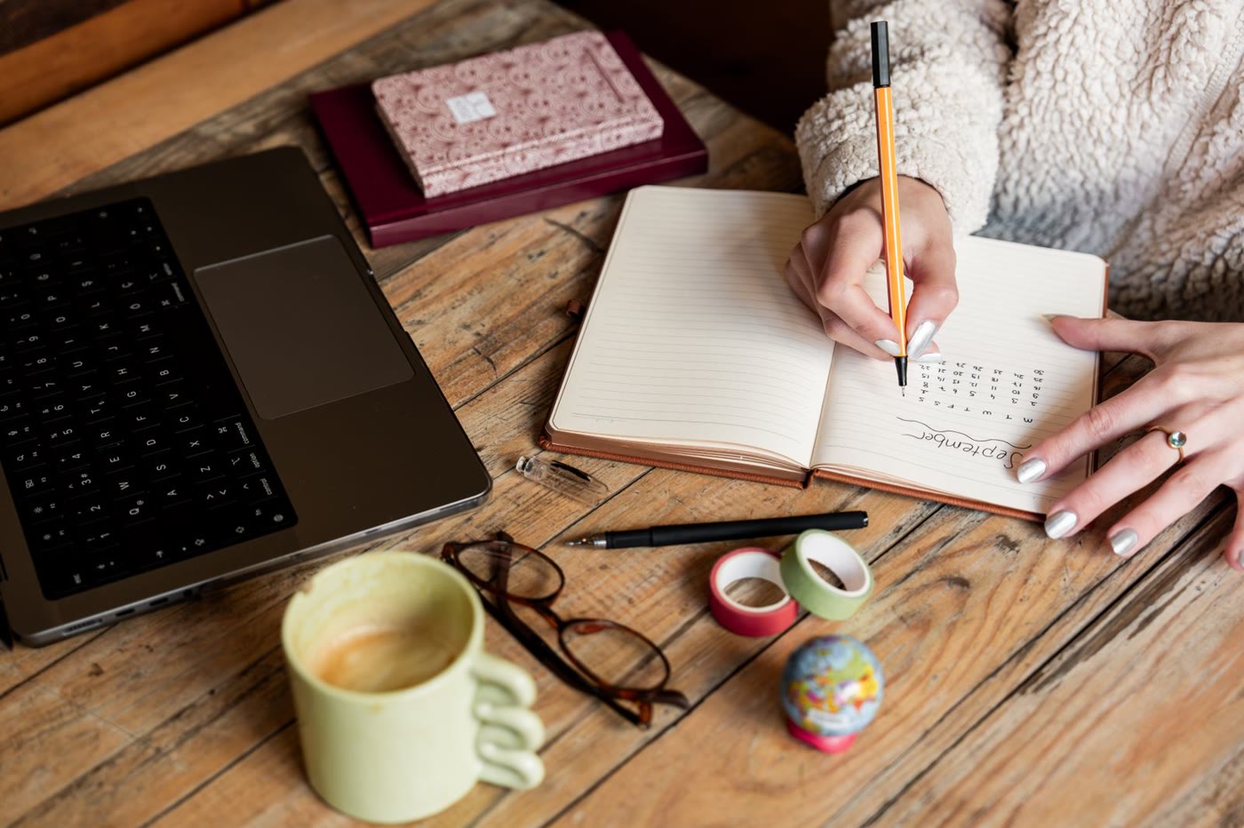 Persona anotando su plan del día en un cuaderno sobre una mesa de madera