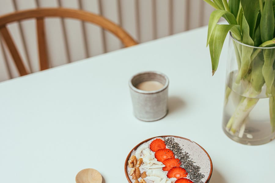 Desayuno ligero con frutas y flores sobre una mesa clara