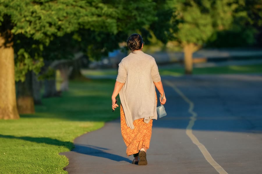 Persona caminando por un sendero del parque en una mañana soleada